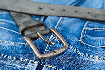 Close-up of vintage leather belt on blue denim jeans