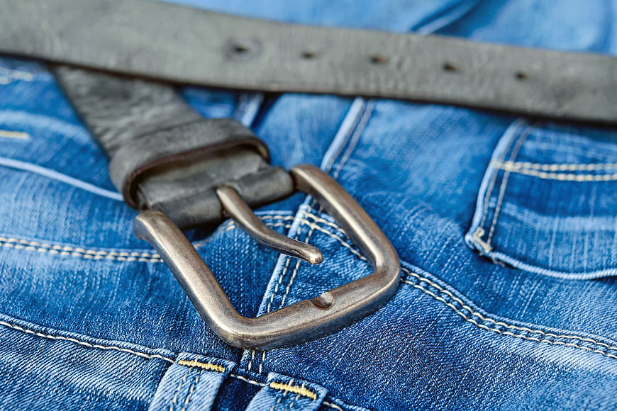 Close-up of vintage leather belt on blue denim jeans
