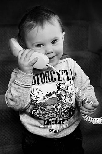 Cute toddler talking on a toy telephone in black and white