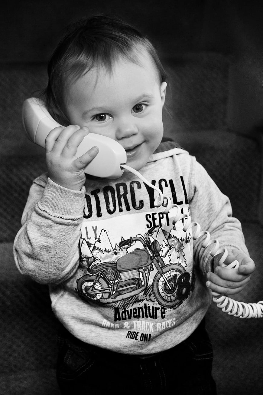 Cute toddler talking on a toy telephone in black and white