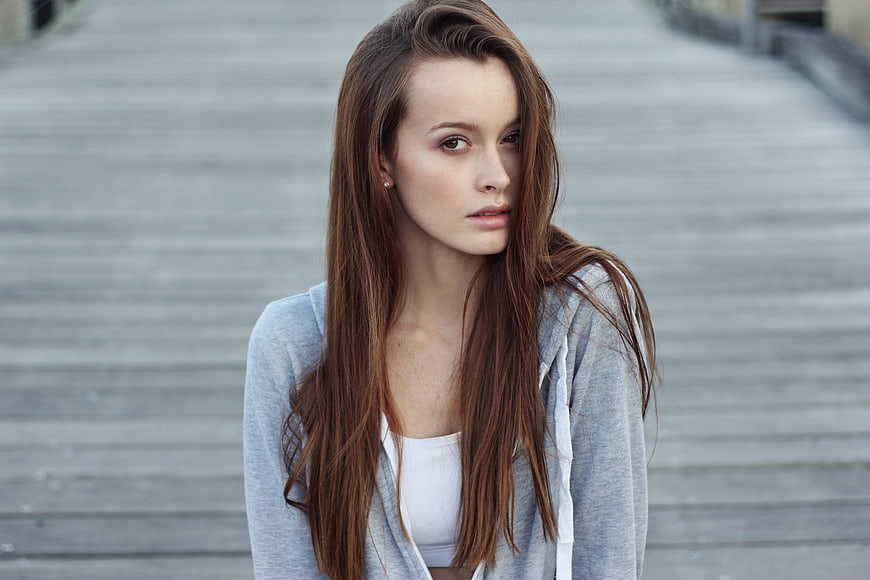 Young woman with long brown hair wearing grey hoodie outdoors