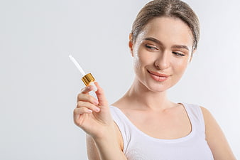 Woman holding skincare serum dropper with copy space