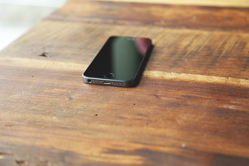 Black smartphone on rustic wooden table surface