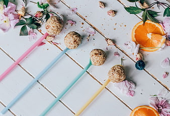 Healthy energy balls on colorful spoons with flowers and oranges