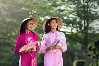 Two Vietnamese Women in Traditional Ao Dai Smiling in Park