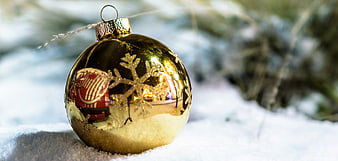 Golden Christmas Ornament in Snow with Snowflake Design