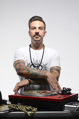 Tattooed DJ scratching on red turntable