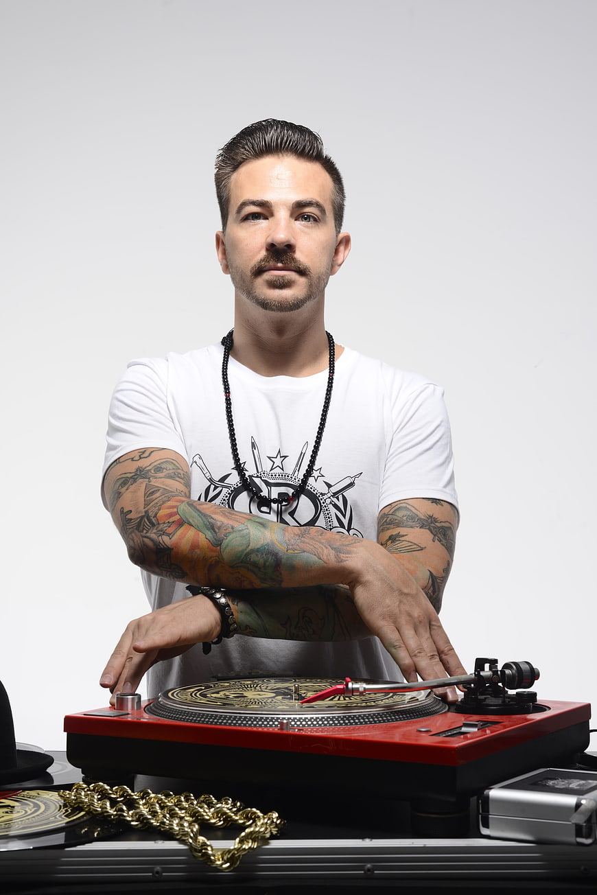 Tattooed DJ scratching on red turntable