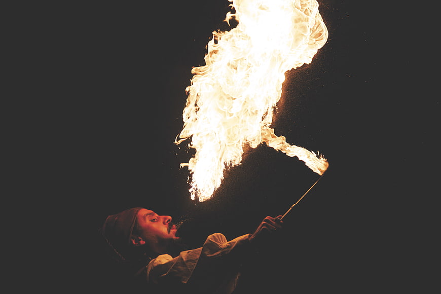 Man performing fire breathing act against dark background