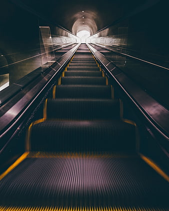 Empty Escalator in Dark Tunnel Leading to Bright Light