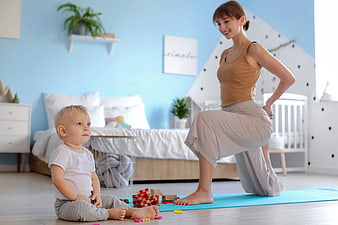 Mother doing yoga while toddler plays with blocks