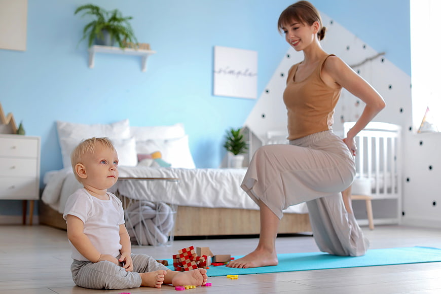 Mother doing yoga while toddler plays with blocks