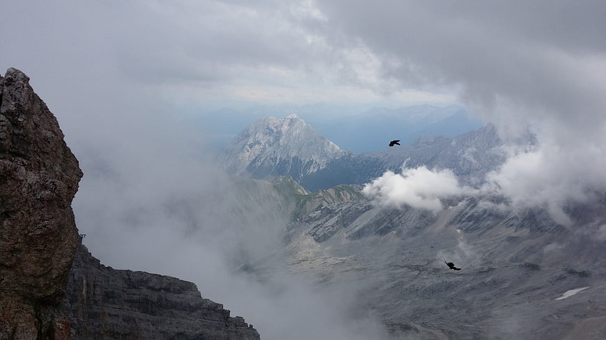 Majestic mountain peaks emerging through clouds with soaring birds