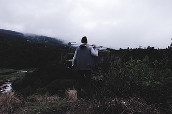 Man carrying tripod on misty mountain ridge