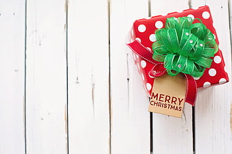 Red Polka Dot Christmas Gift Box with Green Bow on White Wood