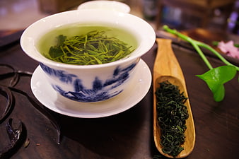 Green tea in blue and white porcelain cup with loose leaves