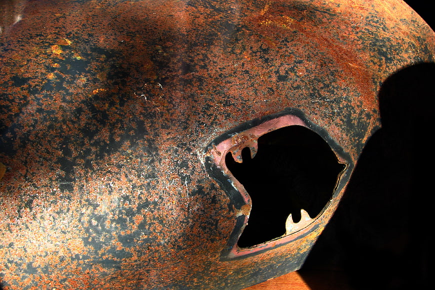 Close-up of rusty metal surface with jagged hole