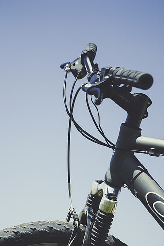 Close-up of bicycle handlebars against blue sky