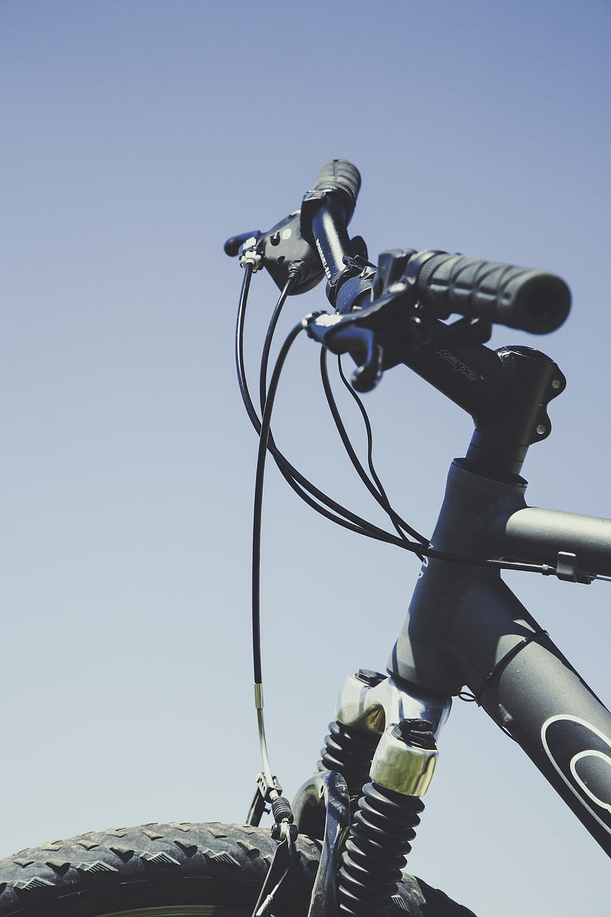 Close-up of bicycle handlebars against blue sky
