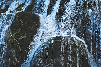 Close-up of rushing waterfall cascading over dark mossy rocks