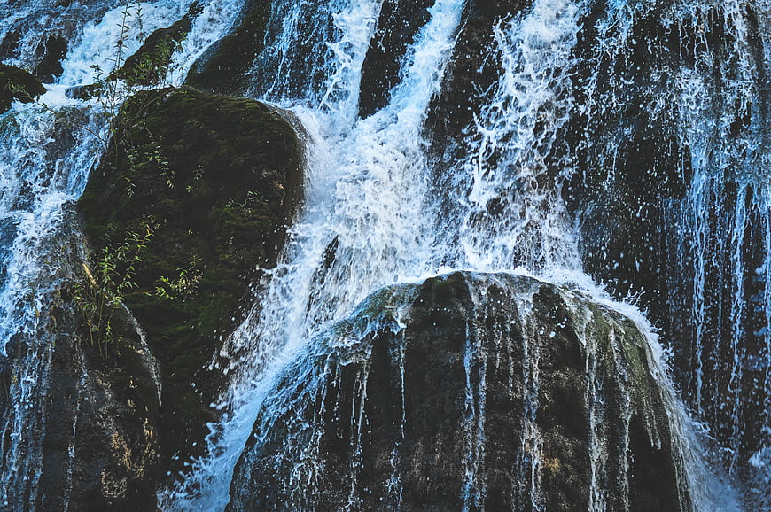 Close-up of rushing waterfall cascading over dark mossy rocks