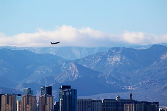Airplane flying over city skyline with mountains