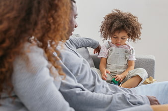 Mother and daughter playing with wooden blocks on sofa
