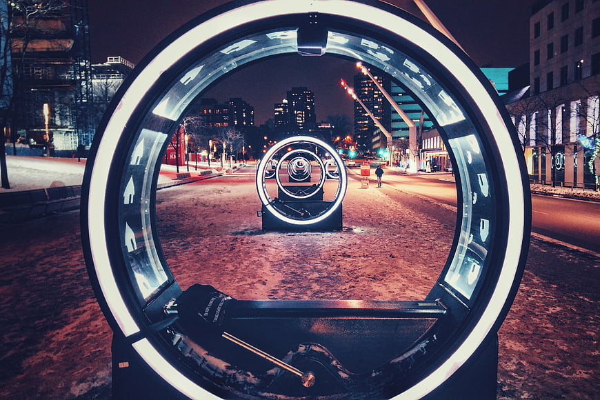 Illuminated circular art installation in snowy city street at night
