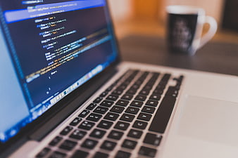 Close-up of laptop screen with code and coffee cup