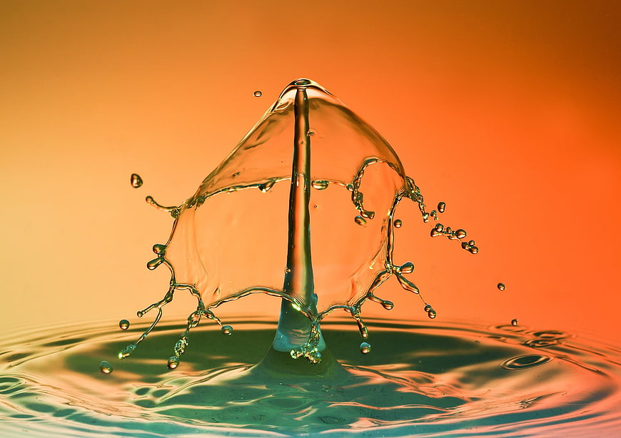 Dynamic water splash crown against warm orange gradient background