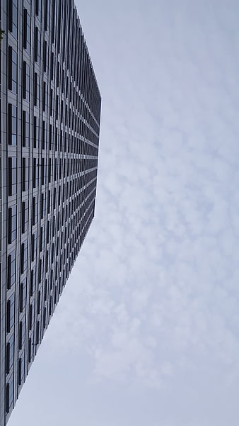 Low angle view of modern skyscraper against cloudy sky
