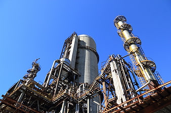 Low Angle View of Industrial Refinery Towers Against Blue Sky