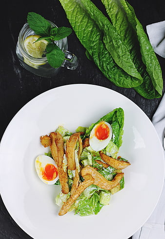 Overhead view of Caesar salad with chicken and soft boiled eggs