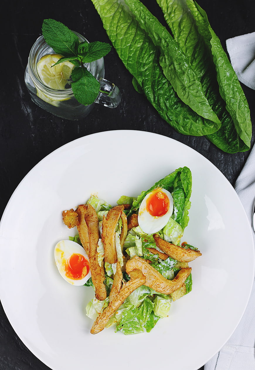 Overhead view of Caesar salad with chicken and soft boiled eggs