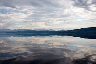 Serene Lake Reflection with Clouds and Distant Mountains