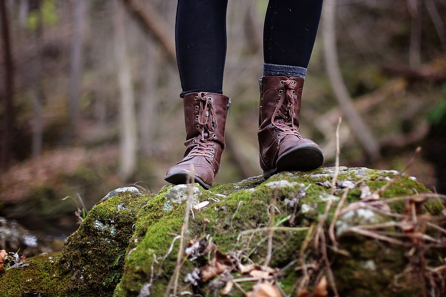 Hiking boots on mossy rock in forest