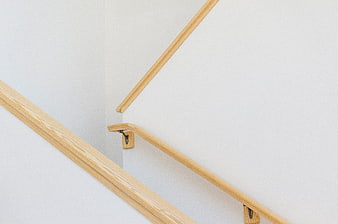 Minimalist wooden handrails on white staircase wall