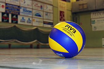 Blue and yellow FIVB volleyball resting on indoor court floor