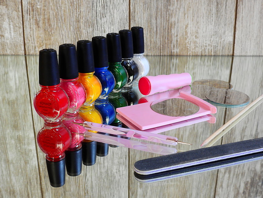 Colorful nail polish bottles and manicure tools on glass table