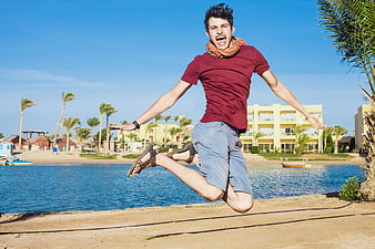 Happy young man jumping in joy by the sea