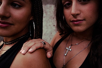 Close-up portrait of two young women with hand on shoulder