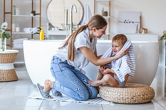Happy Mother Drying Toddler Boy with Towel in Modern Bathroom