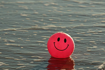 Pink smiley ball floating in ocean waves