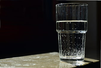 Glass of sparkling water with bubbles on a dark background