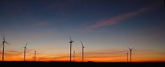 Silhouette of wind turbines against a vibrant sunset sky
