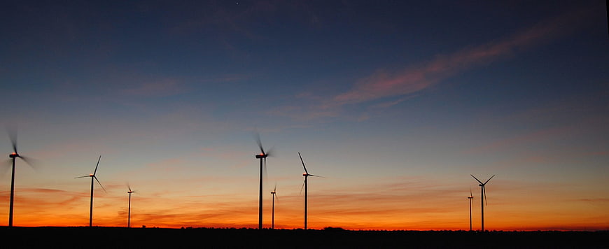 Silhouette of wind turbines against a vibrant sunset sky