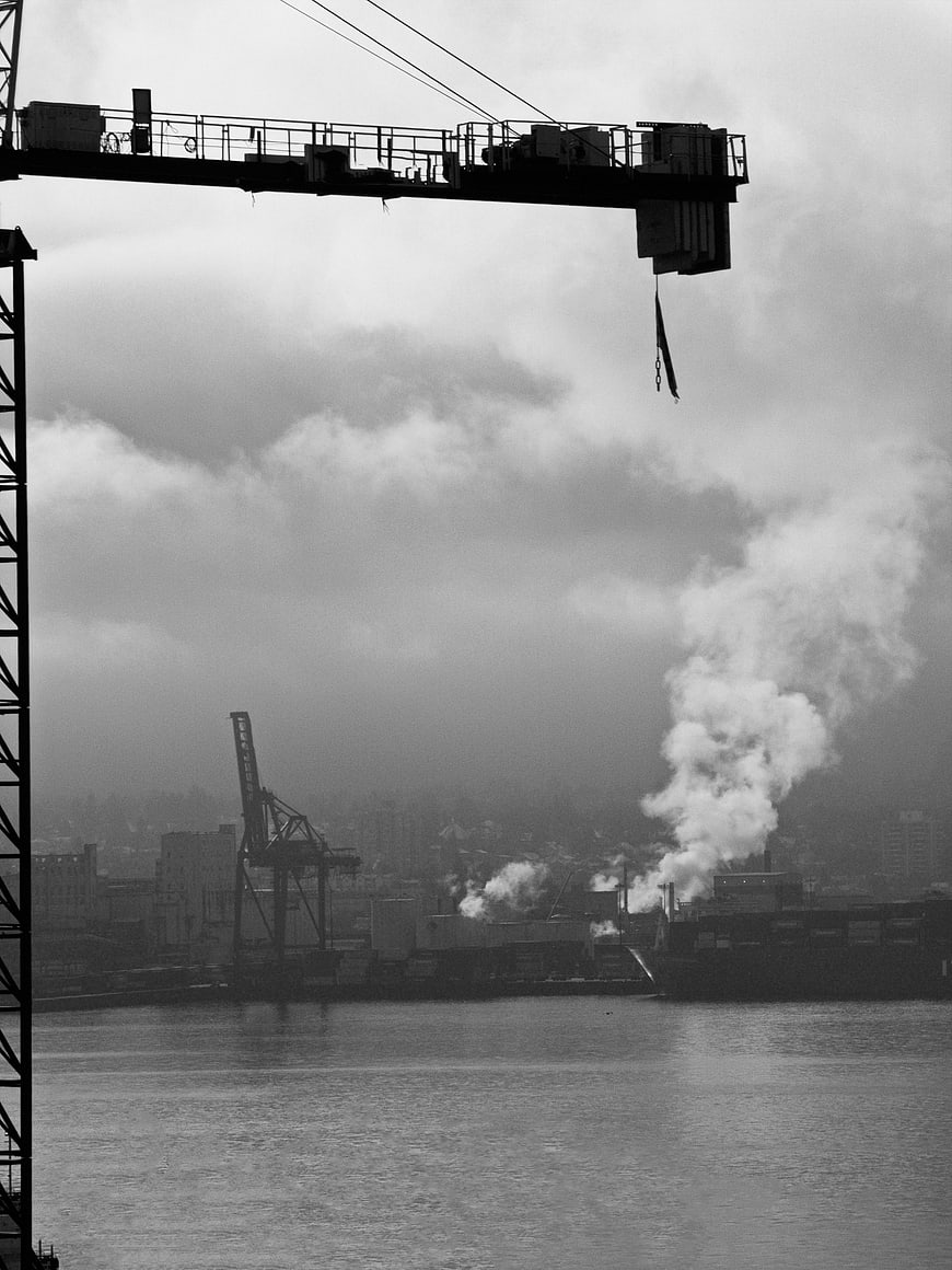 Black and white industrial harbor with crane and steam