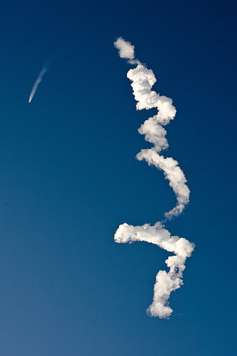 Spiral cloud formation in deep blue sky with contrail
