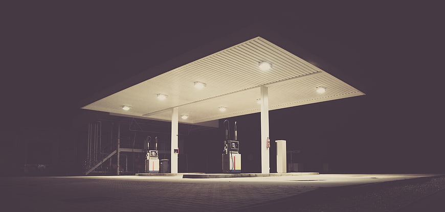Empty illuminated gas station at night with foggy atmosphere