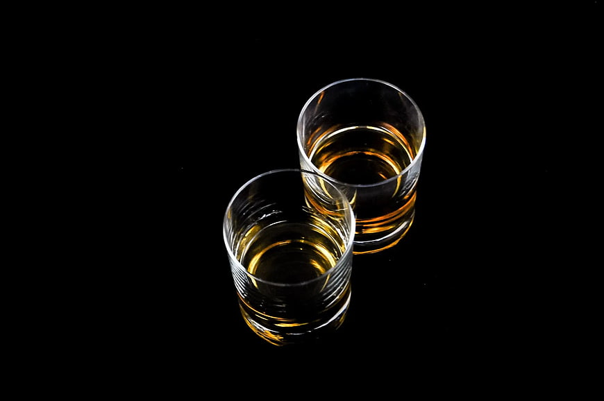 Two Glasses of Amber Liquor on Black Background